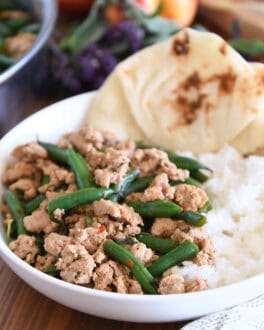White shallow bowl with rice, naan bread, ground turkey and green beans.