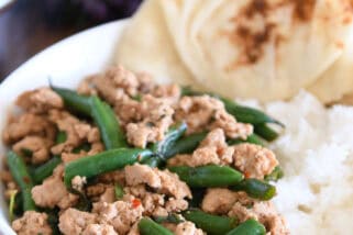 White shallow bowl with rice, naan bread, ground turkey and green beans.