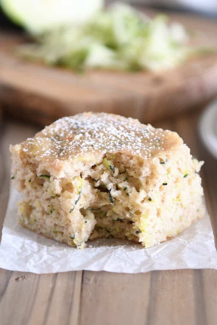 Bite taken out of square of zucchini cake dusted with powdered sugar.