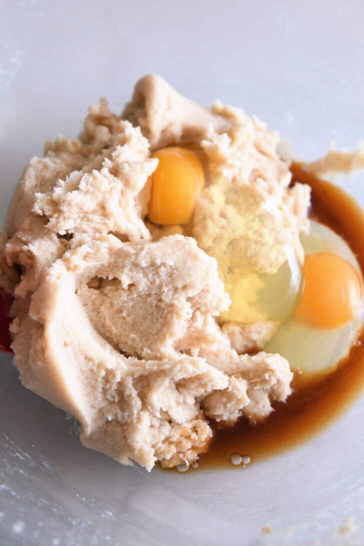 Creamed cookie dough with eggs and vanilla in glass bowl.