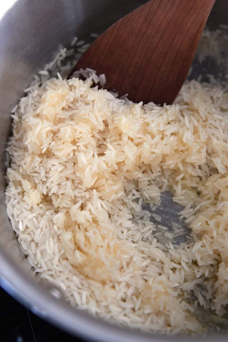 Rice cooking in butter in stainless pot.