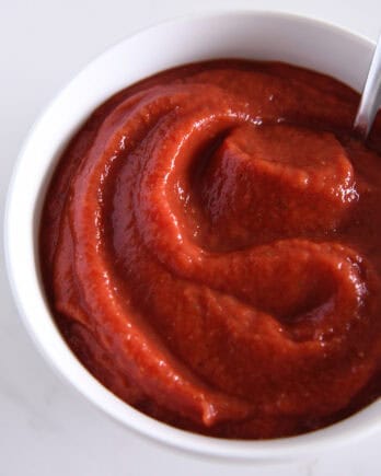 Top down view of a white bowl full of pizza sauce.