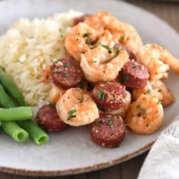 Gray plate with green beans, white rice, shrimp and sausage.