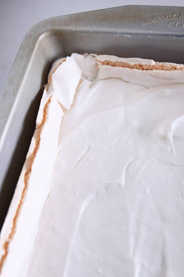 Top down view of a baked meringue dessert in a metal pan.