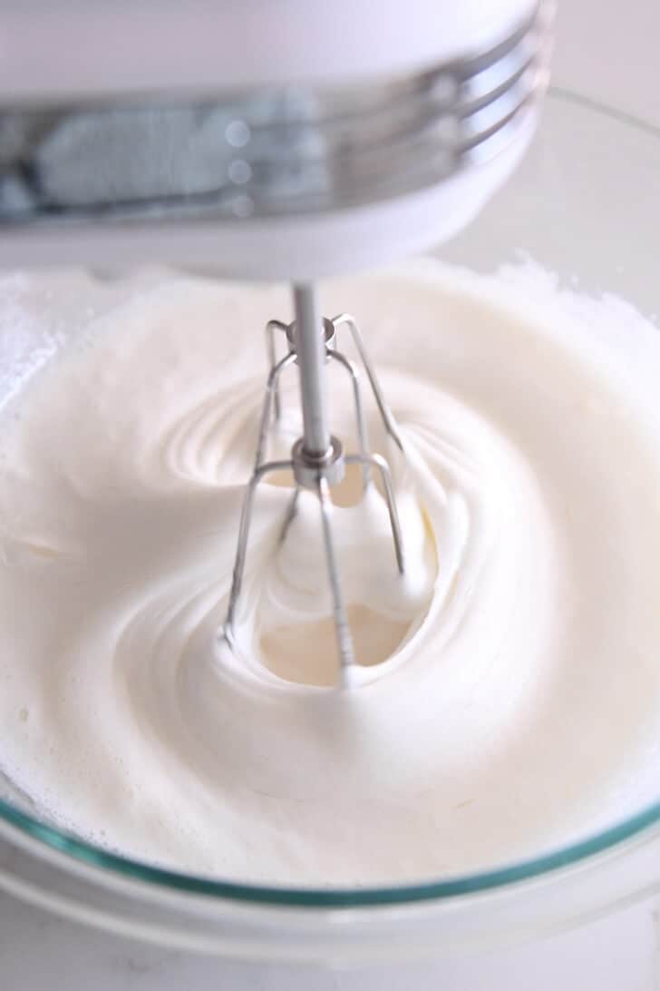 A glass bowl with a mixture mixing egg whites.