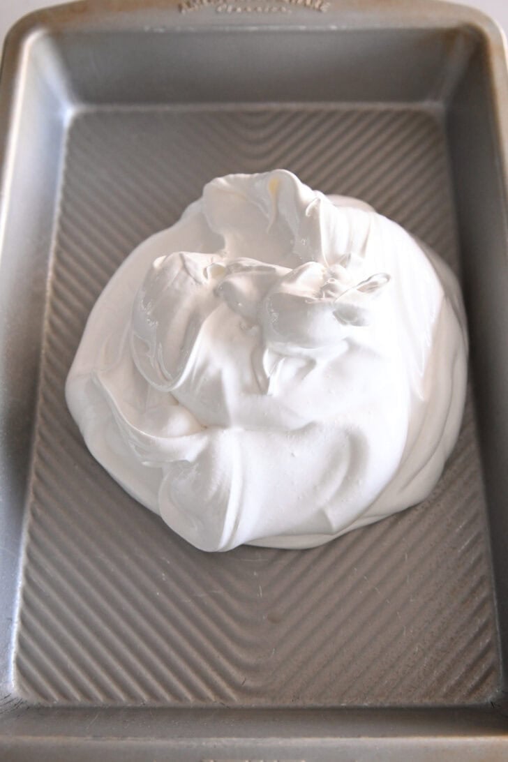 Top down view of a metal pan with a meringue mixture in the middle.