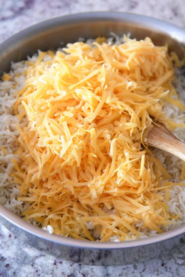 A large pot full of cooked white rice and topped with shredded cheddar cheese.