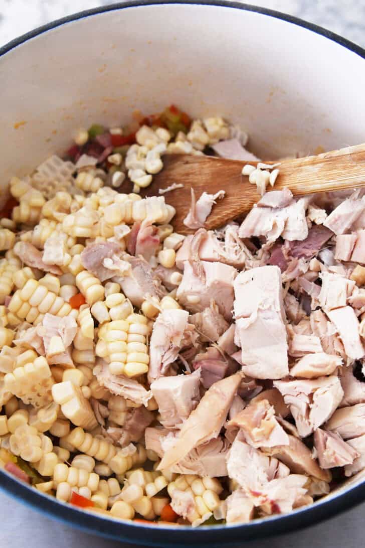 A pot with chopped chicken, fresh corn, and diced vegetables.