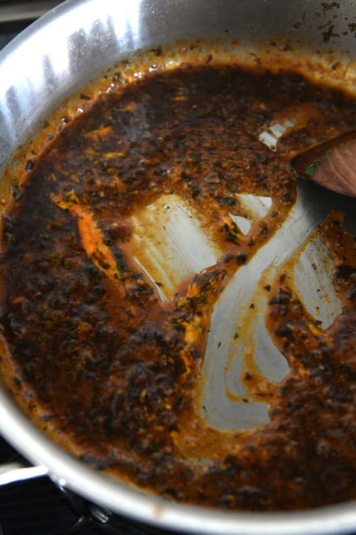 A wooden spoon stirring a dark chipotle sauce in a metal pot.