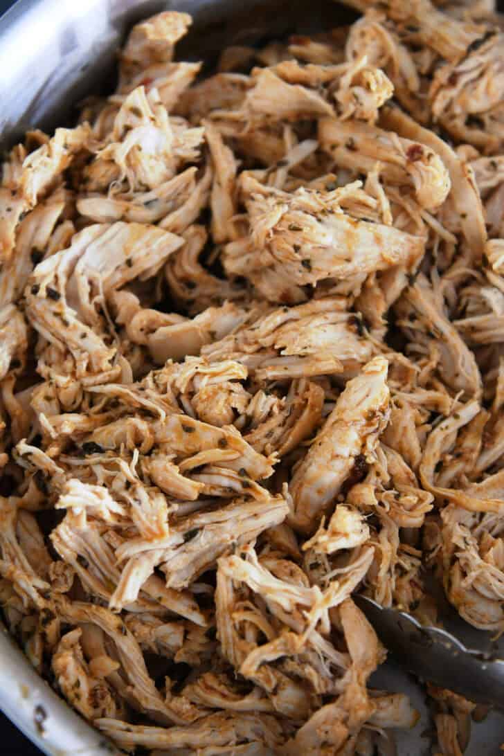 Top down view of seasoned shredded cooked chicken.
