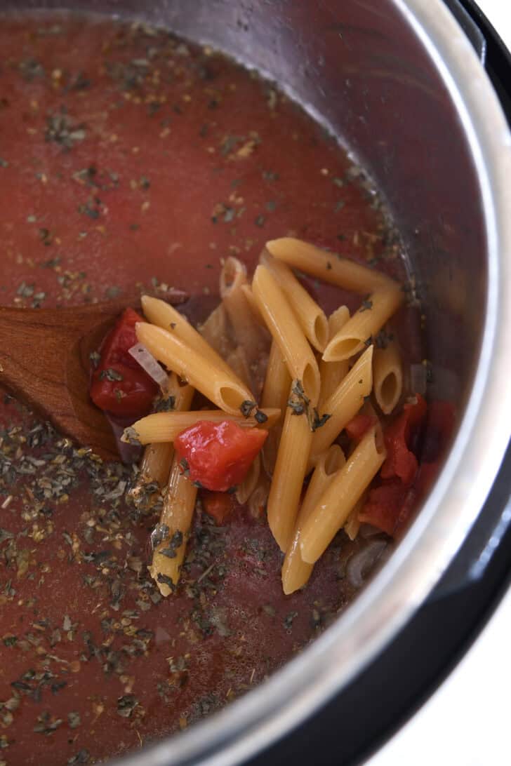Uncooked pasta, diced tomatoes, broth and seasonings in Instant Pot.