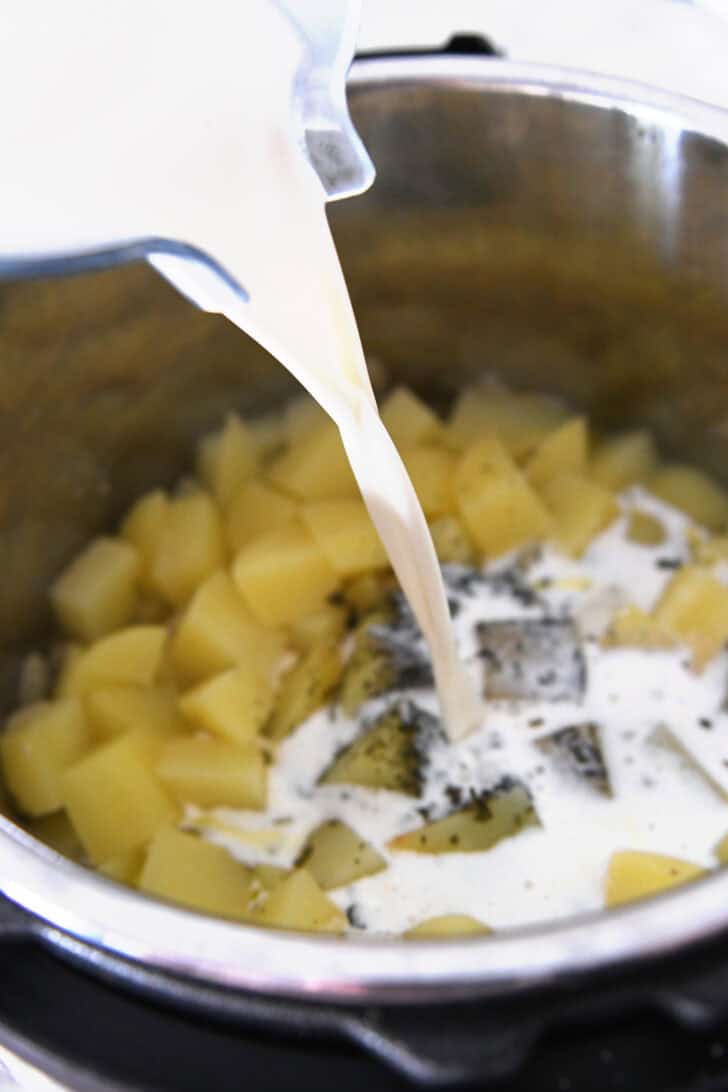 Pouring milk into cooked potatoes in Instant Pot.