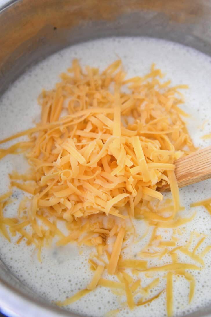 Shredded cheddar cheese added to creamy soup in Instant Pot.