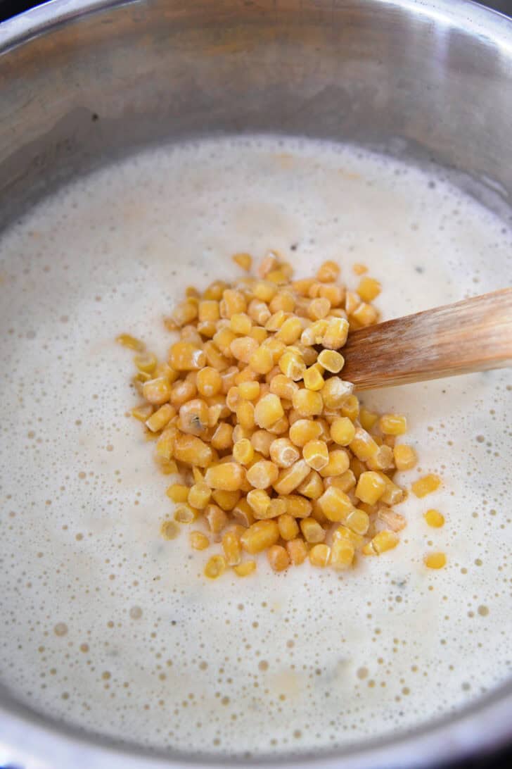 Frozen corn being added to creamy potato soup in instant pot.
