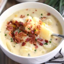 White bowl with potato soup, bacon and chives.