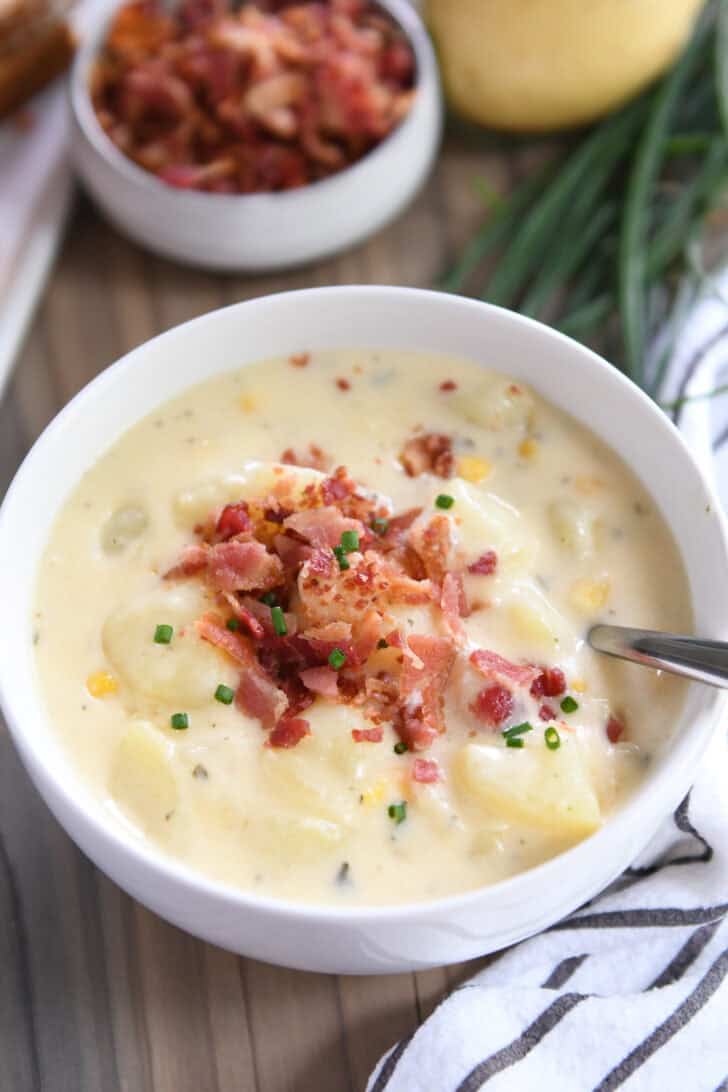 White bowl with creamy potato soup topped with bacon.