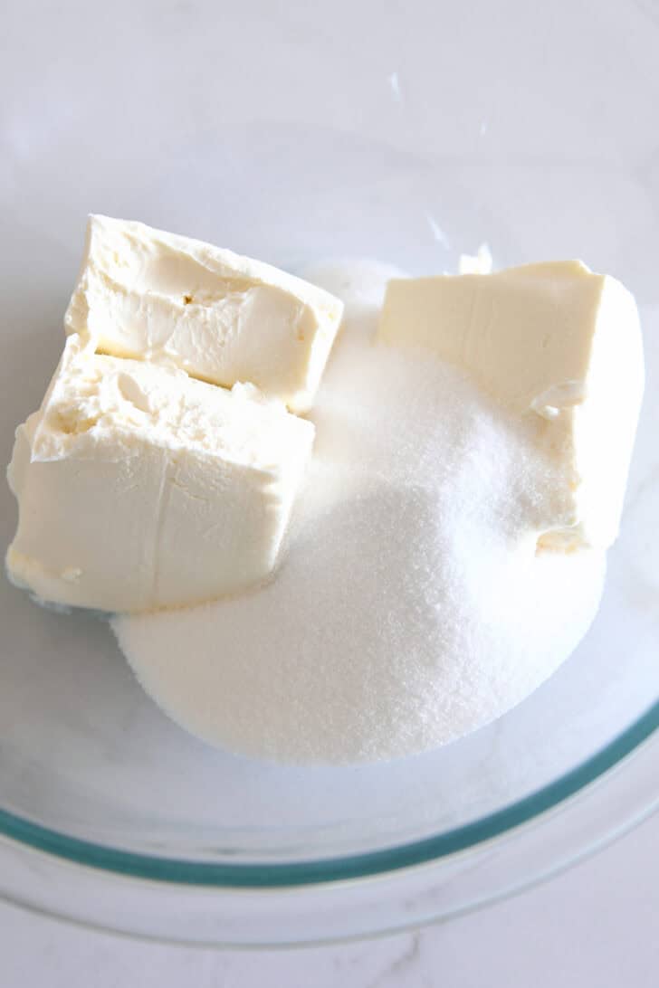 Cream cheese and granulated sugar in glass bowl.