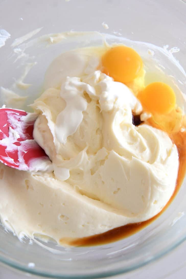 Glass bowl with cheesecake batter, eggs, vanilla and sour cream.