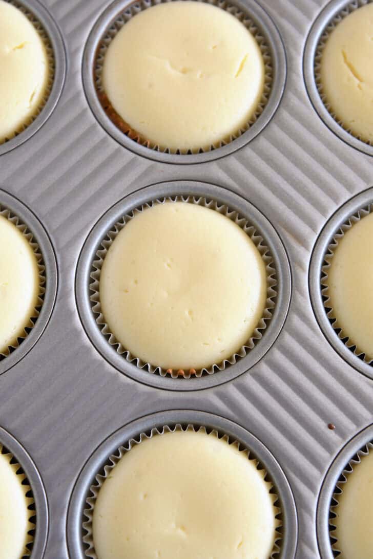 Top down view of baked mini cheesecakes in muffin tin.