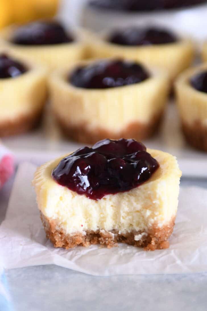 Mini cheesecake with huckleberry topping with bite removed.