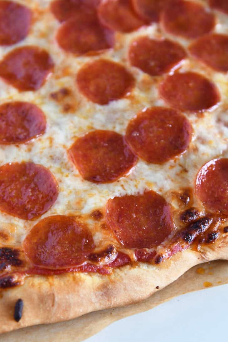 Baked pepperoni pizza on parchment paper.
