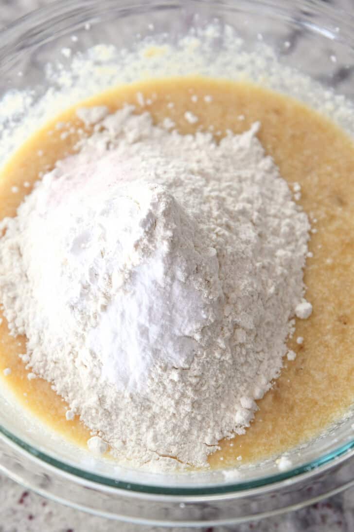 Top down view of ingredients for banana bread in a glass bowl.