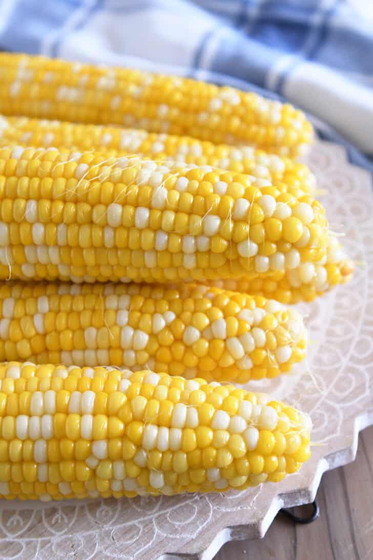 Fresh corn on the cob stacked on top of each other on a decorative platter.