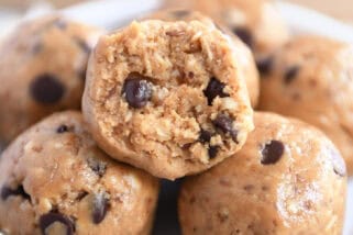 Soft peanut butter chocolate chip balls in a small white dish. The top ball has a bite taken out.
