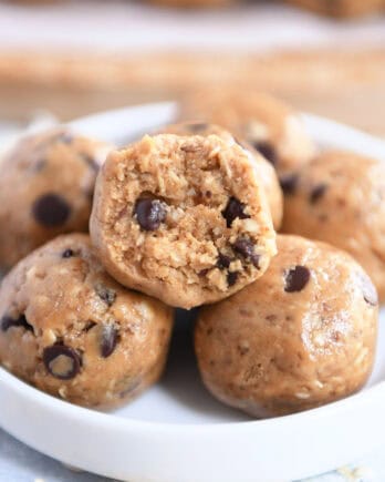 Soft peanut butter chocolate chip balls in a small white dish. The top ball has a bite taken out.