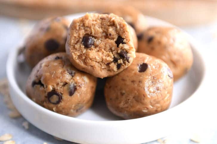Soft peanut butter chocolate chip balls in a small white dish. The top ball has a bite taken out.