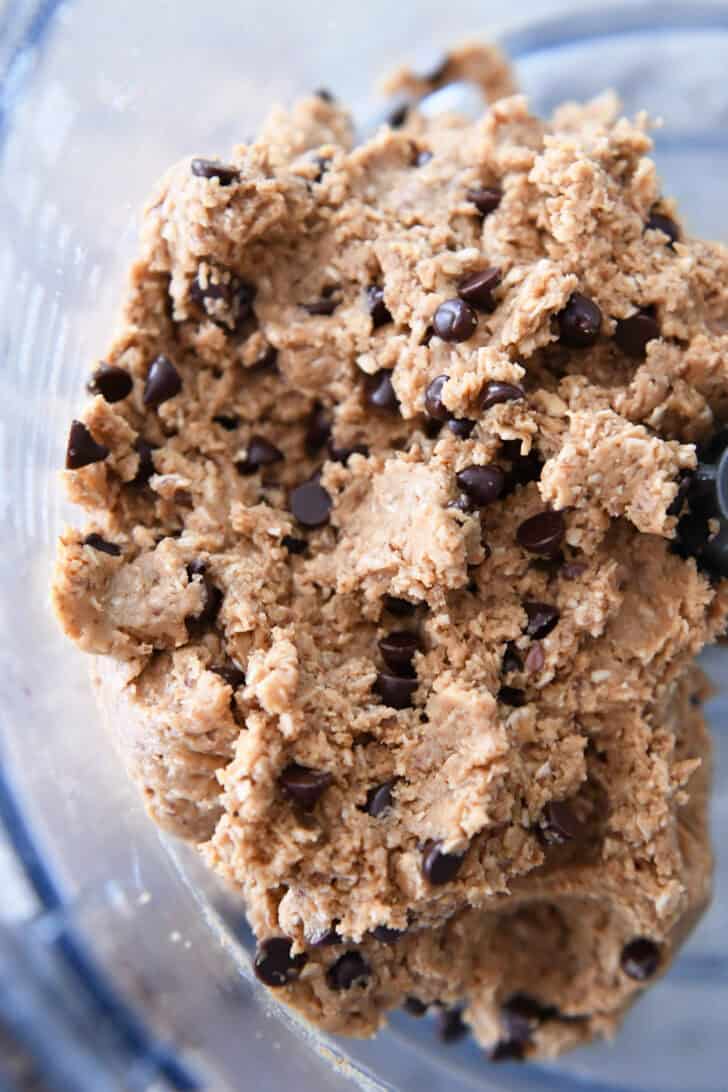 Top down view of a chocolate chip peanut butter oat dough in the bottom of a food processor.