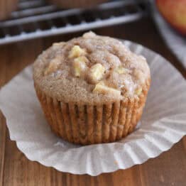 Unwrapped apple muffin on paper liner.