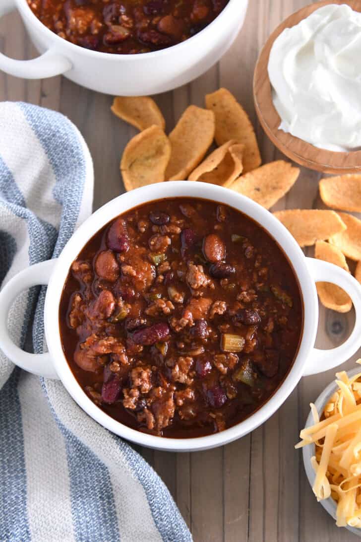 Top down view of southern beef and bean tomato chili in white bowl with handles.