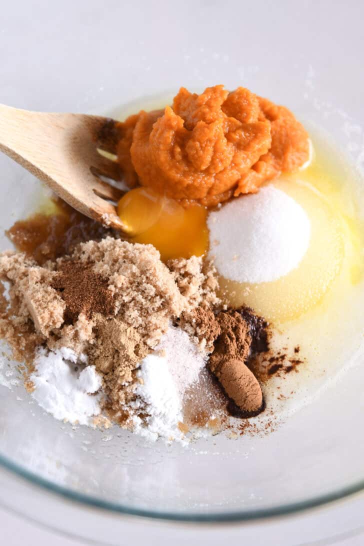 Glass bowl with canned pumpkin, egg yolk, brown sugar, granulated sugar, brown butter, and cinnamon.