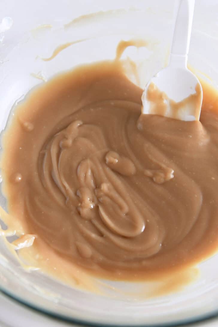 Glass bowl filled with caramel sauce mixed with cream cheese.