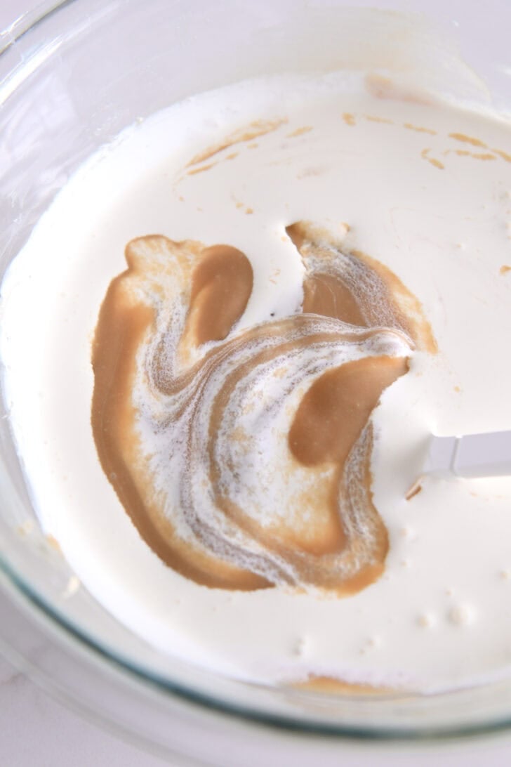 Glass bowl with caramel sauce and whipped cream.