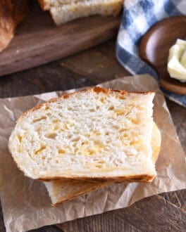 Top down view of half slice of cheesy peasant bread on brown parchment paper.