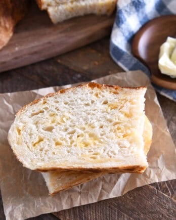Top down view of half slice of cheesy peasant bread on brown parchment paper.