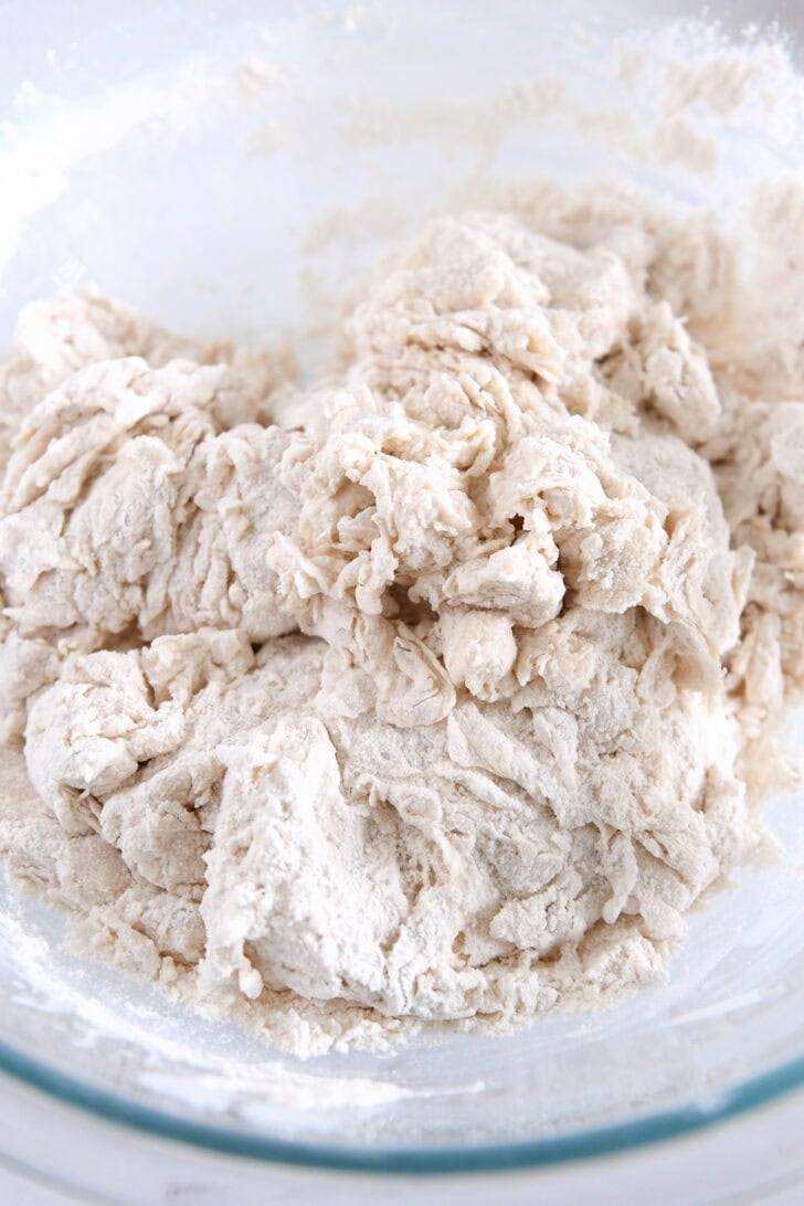 Shaggy bread dough mixed in glass bowl.