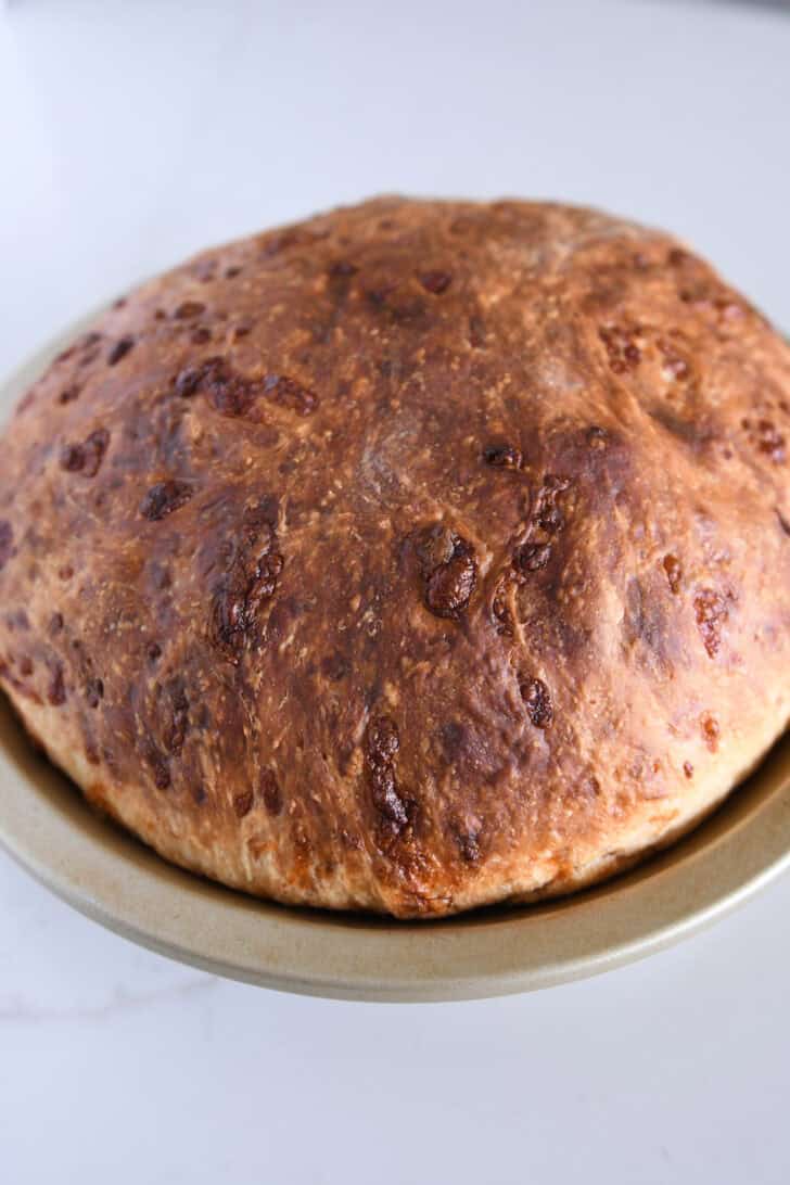 Baked loaf of cheesy peasant bread in pie plate.
