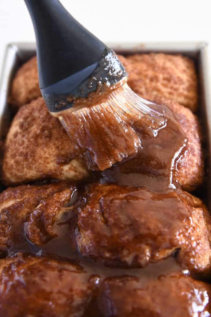 Brushing butter, cinnamon and brown sugar over top of hot baked cinnamon bread.