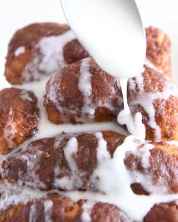 Spoon drizzling glaze over cinnamon bread.