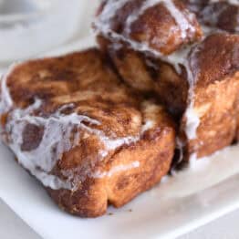 Thick slice of cinnamon bread on white platter with glaze.