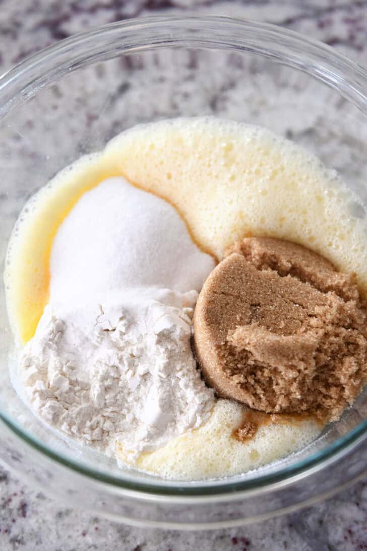 Top down view of ingredients for chocolate chip cookies in a glass bowl.