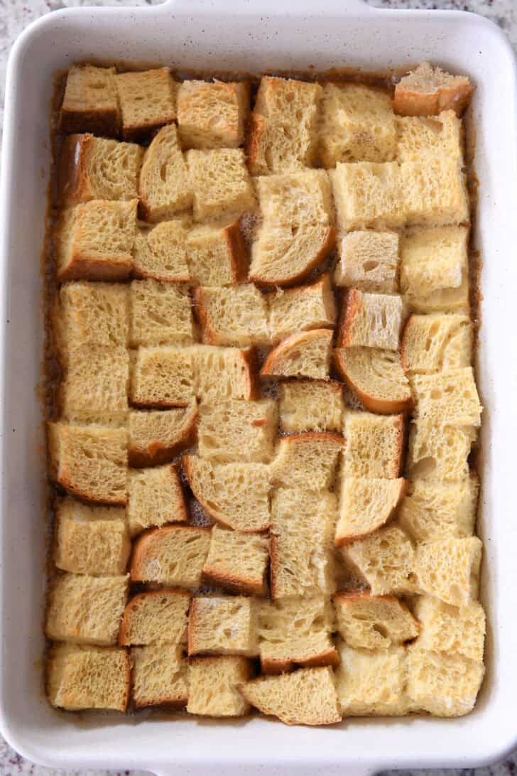 Top down view of a white ceramic dish with egg-coated bread on the bottom of the dish.