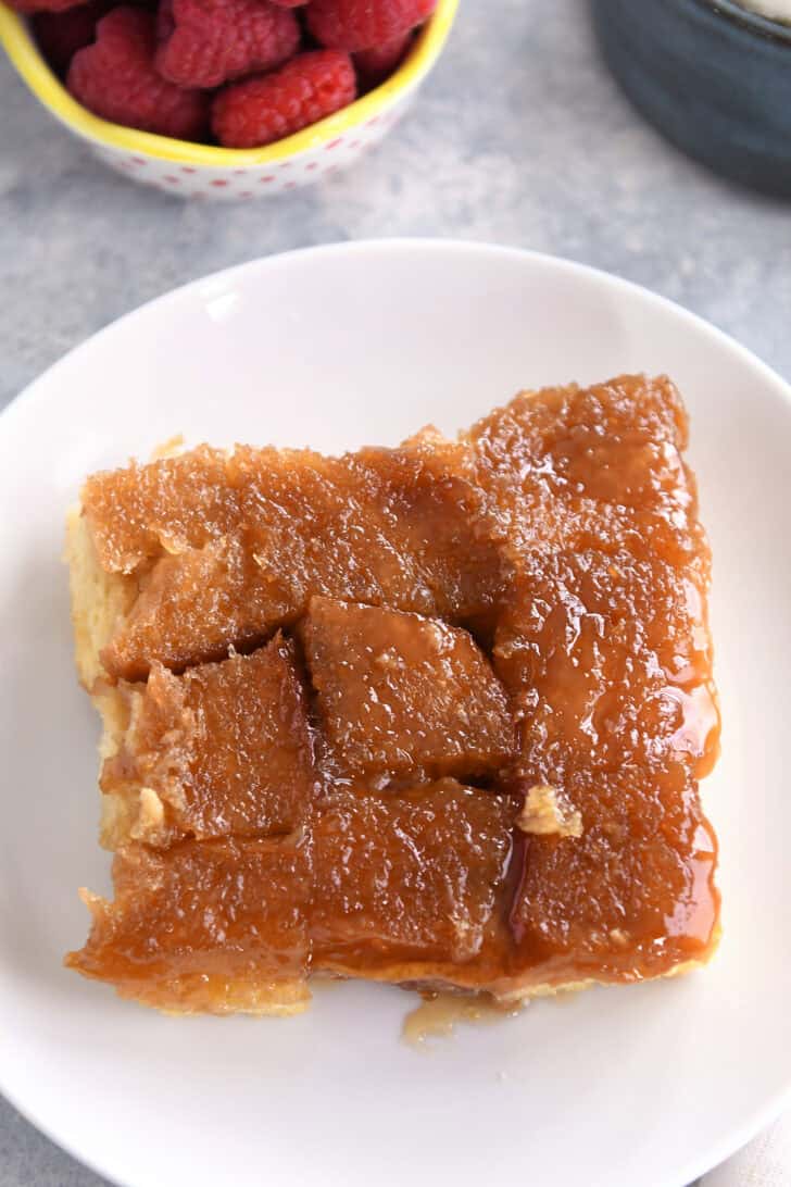 Top down view of a piece of sticky coated french toast bake on a white plate.