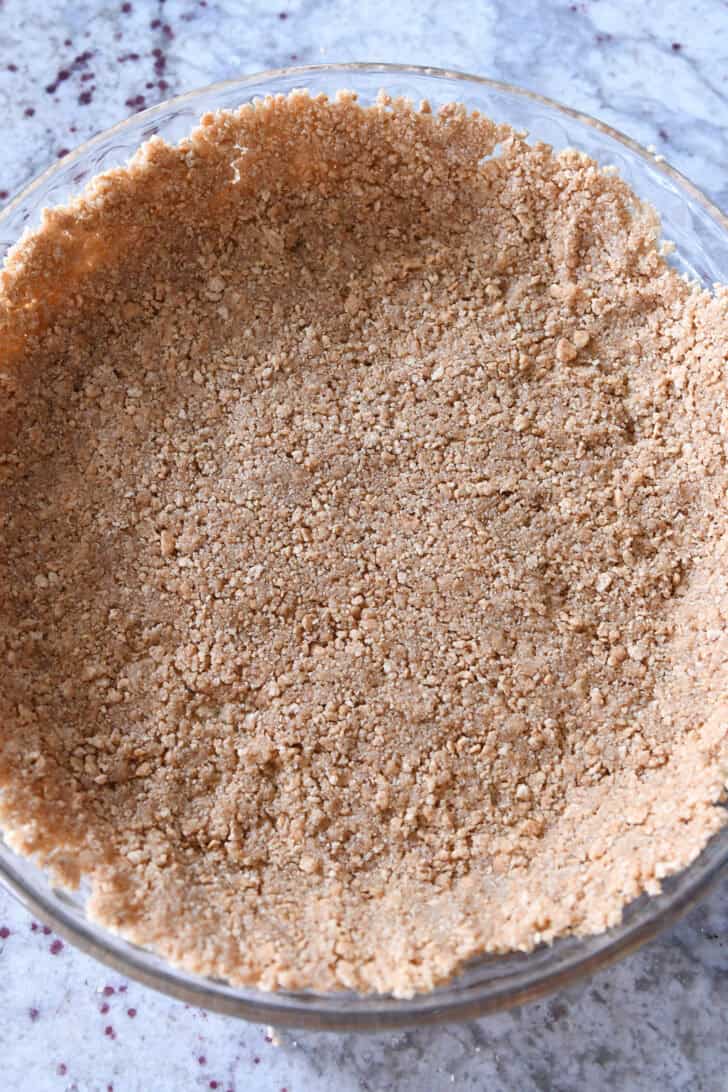 Top down view of a graham cracker crust in a glass pie plate.