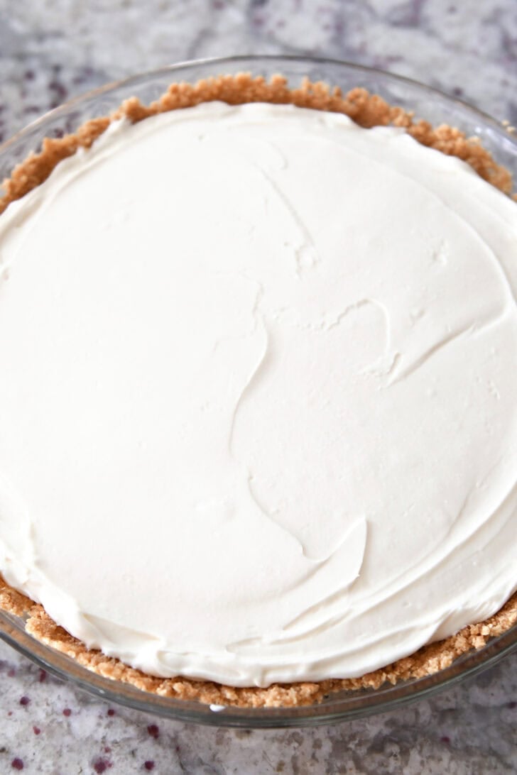 Top down view of a cheesecake with a graham cracker crust in a glass pie dish.