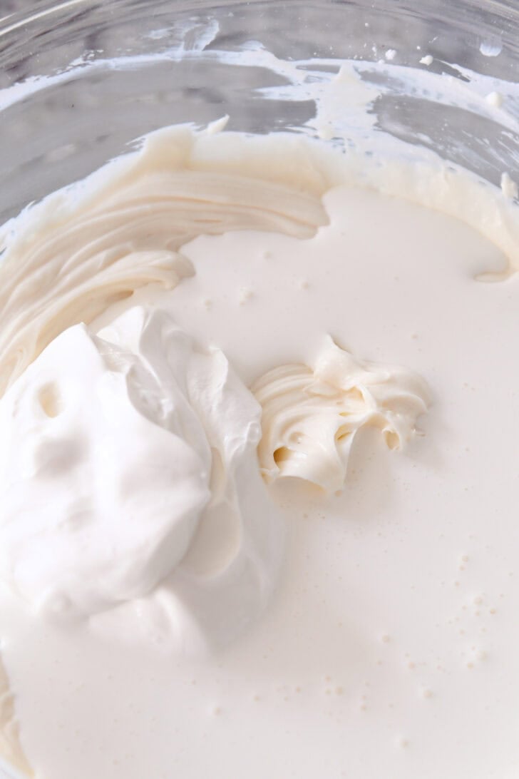 Top down view of a glass bowl with a cheesecake mixture ready to be whipped.