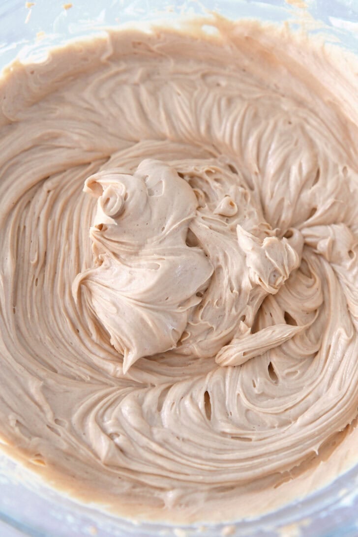 Top down view of a glass bowl with a creamy whipped peanut butter mixture inside.